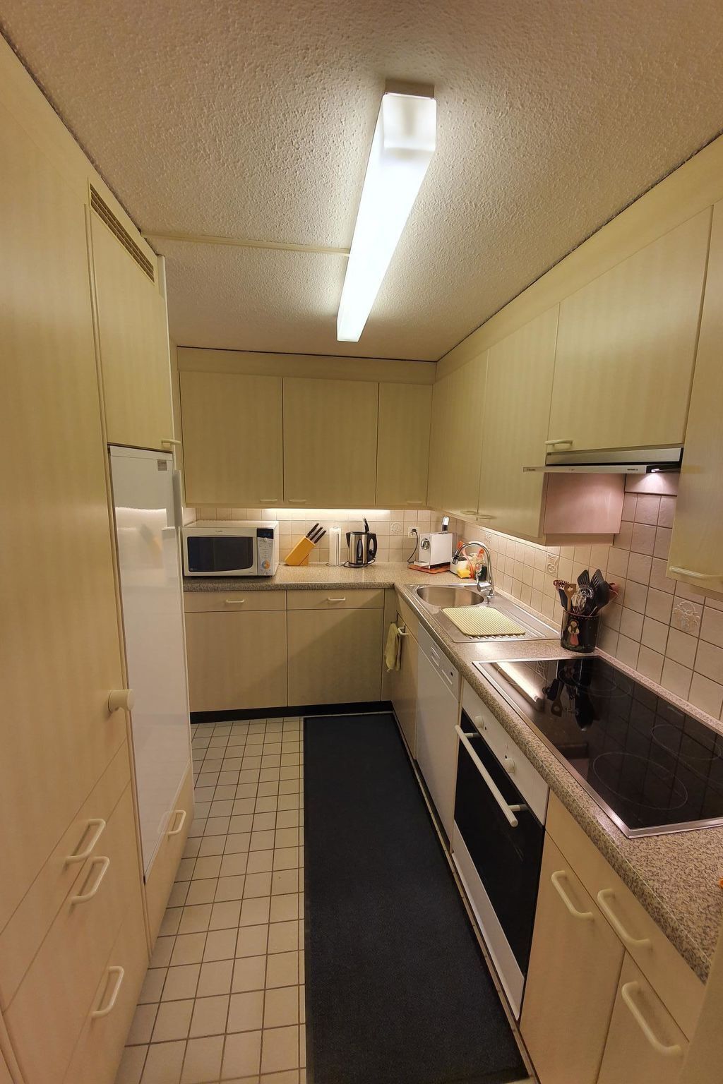 Une cuisine de taille réduite équipée d’un four à micro-ondes, d’une cuisinière, d’un évier et de placards.