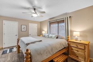 A bedroom with a bed, bedside tables, a ceiling fan, and a window with curtains.