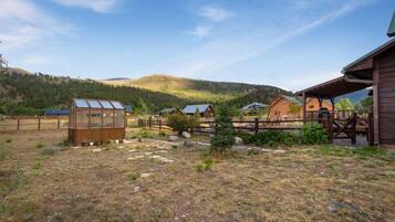A rustic cabin with a wooden deck and a glass greenhouse.