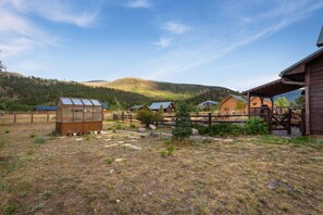 A rustic cabin with a wooden deck and a glass greenhouse.