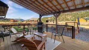 Eine überdachte Terrasse im Freien mit Holzmöbeln und einem Grill.