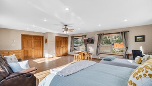 Ein Schlafzimmer mit Bett, Schreibtisch, Stuhl und einer Couch. Es gibt zwei Türen und ein Fenster.