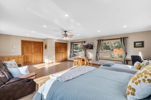 Een slaapkamer met een bed, een bureau, een stoel en een bank. Er zijn twee deuren en een raam.