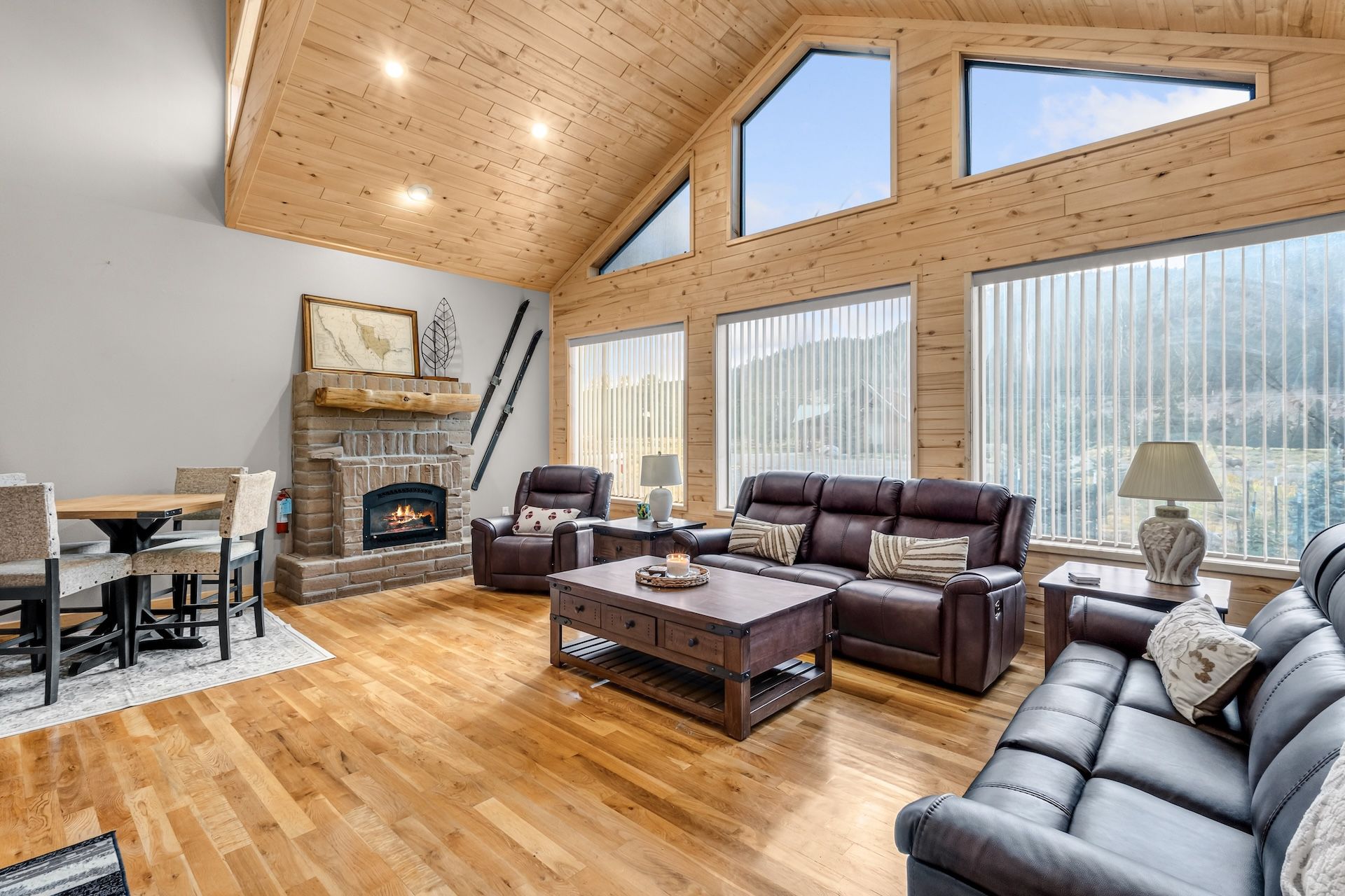 A spacious living room with a fireplace, leather sofas, and large windows.