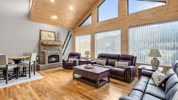 A spacious living room with a fireplace, leather sofas, and large windows.