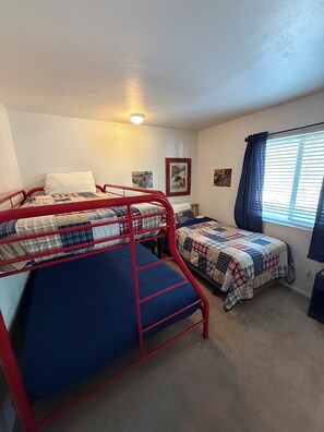 A dormitory room with bunk beds, a single bed, a window with curtains, and wall-mounted pictures. - Unique Big Bear Experience, Family Game Room, plenty of space to lounge - BEST location to everything! Hot tub and huge yard, great for sledding. So close to downtown - walk to The Village for boutique shopping! (Big Bear Lake)