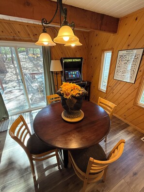 A wooden interior with a round table, chairs, a decorative vase, a gaming console, and a wildlife poster. - Unique Big Bear Experience, Family Game Room, plenty of space to lounge - BEST location to everything! Hot tub and huge yard, great for sledding. So close to downtown - walk to The Village for boutique shopping! (Big Bear Lake)