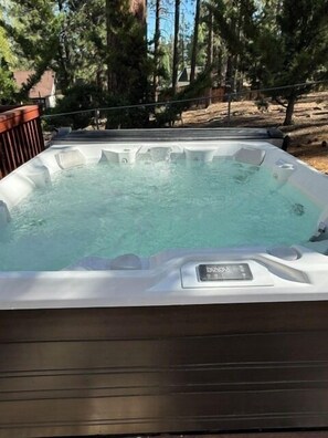 A hot tub with a control panel, surrounded by trees and a wooden deck. - Unique Big Bear Experience, Family Game Room, plenty of space to lounge - BEST location to everything! Hot tub and huge yard, great for sledding. So close to downtown - walk to The Village for boutique shopping! (Big Bear Lake)
