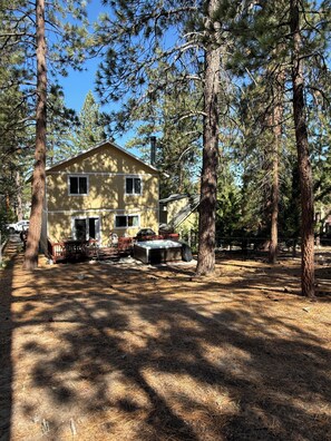 A two-story house surrounded by tall pine trees, with a hot tub and outdoor furniture visible. - Unique Big Bear Experience, Family Game Room, plenty of space to lounge - BEST location to everything! Hot tub and huge yard, great for sledding. So close to downtown - walk to The Village for boutique shopping! (Big Bear Lake)