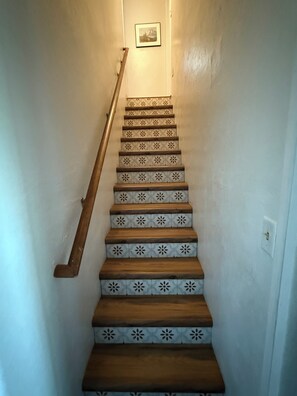 A staircase with patterned steps and a wooden handrail. - Unique Big Bear Experience, Family Game Room, plenty of space to lounge - BEST location to everything! Hot tub and huge yard, great for sledding. So close to downtown - walk to The Village for boutique shopping! (Big Bear Lake)