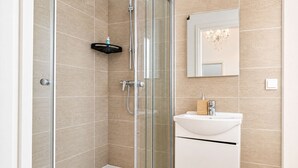 A modern bathroom with a glass shower enclosure, a white sink, and a mirror above it.