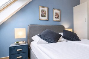 A bedroom with a bed, bedside tables, a lamp, and framed pictures on the wall. - Cozy AC Room Near Hauptbahnhof | Smart TV & Self Check-In (Vienna)