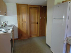 A kitchen with a refrigerator, a sink, and wooden cabinets. - Stockbrunä Appartement/Fewo, Bad, WC, 2 Schlafräume by Interhome (Adelboden)