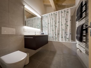 A bathroom with a toilet, a sink, a mirror, and a shower area. - Ferienwohnung Bunder (DG) Appartement/Fewo, Bad, WC, 3 Schlafräume by Interhome (Adelboden)