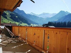 Ein Balkon mit Holzgeländer mit Blick auf eine gebirgige Landschaft.