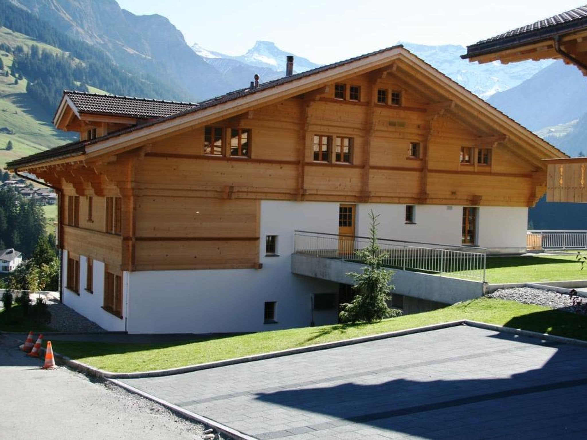 Un edificio in legno di due piani con un balcone, circondato da un prato curato e da un vialetto lastricato.