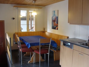 A compact kitchen with a dining table, chairs, a sink, and a window with a view. - Chalet Sunnegg Appartement/Fewo, Dusche, WC, 2 Schlafräume 3-Zimmerwohnung by Interhome (Adelboden)