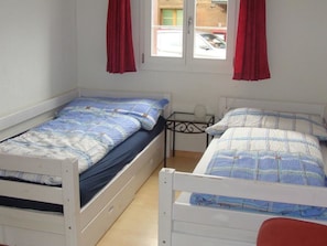 A room with two single beds, each with a blue and white patterned bedspread, and a small table between them. - Chalet Sunnegg Appartement/Fewo, Dusche, WC, 2 Schlafräume 3-Zimmerwohnung by Interhome (Adelboden)