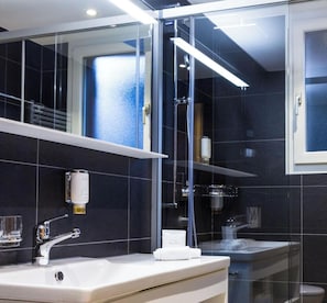 Ein modernes Badezimmer mit Duschkabine aus Glas, einem weißen Waschbecken und einem Spiegel.