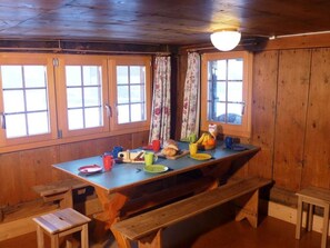 Ein Essbereich aus Holz mit einem großen Tisch, Bänken und fensterbepflanzten Fenstern.