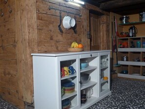 Eine Küche mit Holzwänden, einem weißen Schrank mit Glastüren und einem gefliesten Boden.