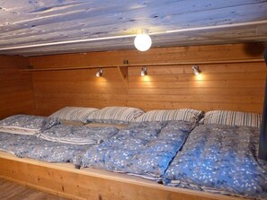 Ein Holzblock-Interieur mit Bett, Holzwänden und einer Deckenleuchte.