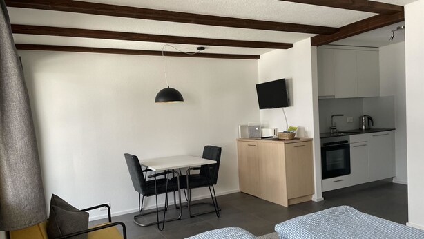 Habitación pequeña con cama, escritorio y kitchenette.