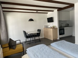 A compact room with a bed, a desk, and a kitchenette. - Helios Studio Appartement/Fewo, Bad, WC, 1 Schlafraum 1-Zimmerwohnung by Interhome (Adelboden)