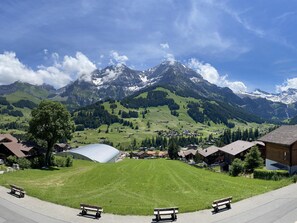 A mountain landscape with a village, a large building, and benches along a path. - Helios Studio Appartement/Fewo, Bad, WC, 1 Schlafraum 1-Zimmerwohnung by Interhome (Adelboden)