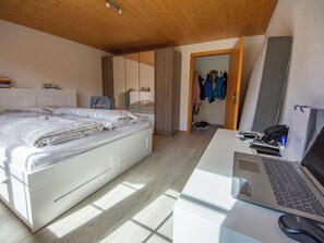 Ein Schlafzimmer mit einem Bett, einem Schreibtisch mit einem Laptop und einem Kleiderschrank.