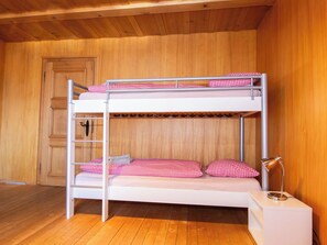 Uma cama beliche com escada, mesa de cabeceira e abajur.