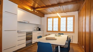 Eine moderne Küche mit weißen Schränken, einem eingebauten Ofen und einem Essbereich mit Tisch und Stühlen.