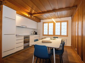 Eine moderne Küche mit weißen Schränken, einem eingebauten Ofen und einem Essbereich mit Tisch und Stühlen.