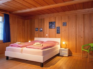 Ein Zimmer mit Holzwänden, einem Doppelbett, Nachttischlampen und einem grünen Sessel.