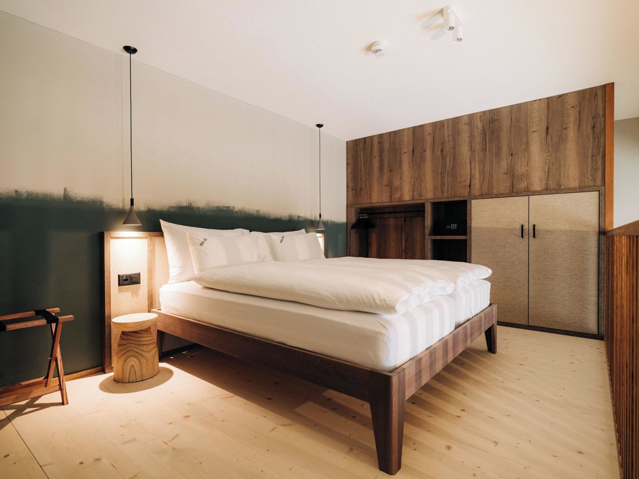 Quarto com cama de madeira, mesa de cabeceira, luminária e guarda-roupa.