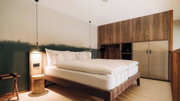 A bedroom with a wooden bed, a bedside table, a lamp, and a wardrobe. - KURVE Apartments & Lounge Appartement/Fewo, Bad, WC, 2 Schlafräume by Interhome (Adelboden)
