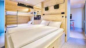 Una camera compatta con un letto a castello, angolo cottura e una piccola scrivania.