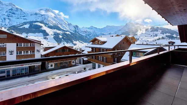 Paesaggio montano innevato con edifici in legno e un balcone con vista.