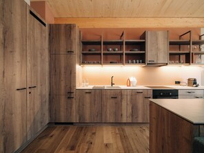 Une cuisine moderne avec des meubles en bois, un plan de travail et une étagère intégrée.