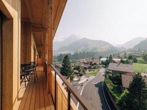 Un balcón de madera con vistas a un paisaje montañoso y una carretera.