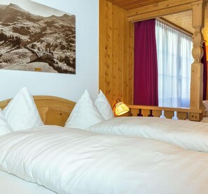 Een bed met witte lakens, een houten hoofdbord en een nachtkastje met een lamp.