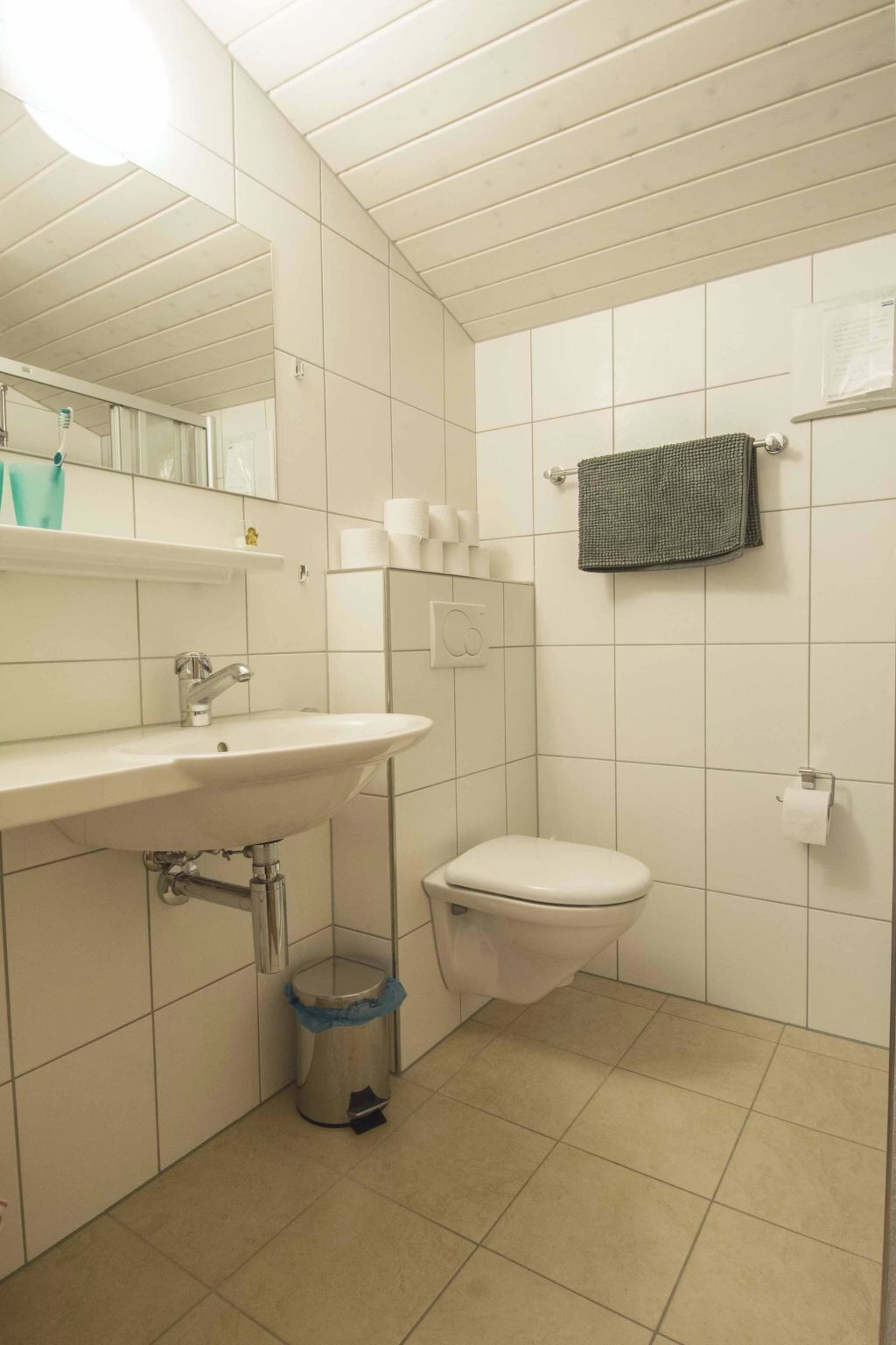 Un baño con un lavamanos blanco, un inodoro y un espejo.