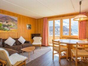 A cozy living room with a brown leather sofa, a white furry chair, a wooden coffee table, and a dining area with a wooden table and chairs. - Chalet Buchhüttli Appartement/Fewo, Dusche oder Bad, WC, 2 Schlafräume by Interhome (Adelboden)