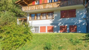 Eine zweistöckige Chalet mit Balkon, vor einer Berglandschaft.