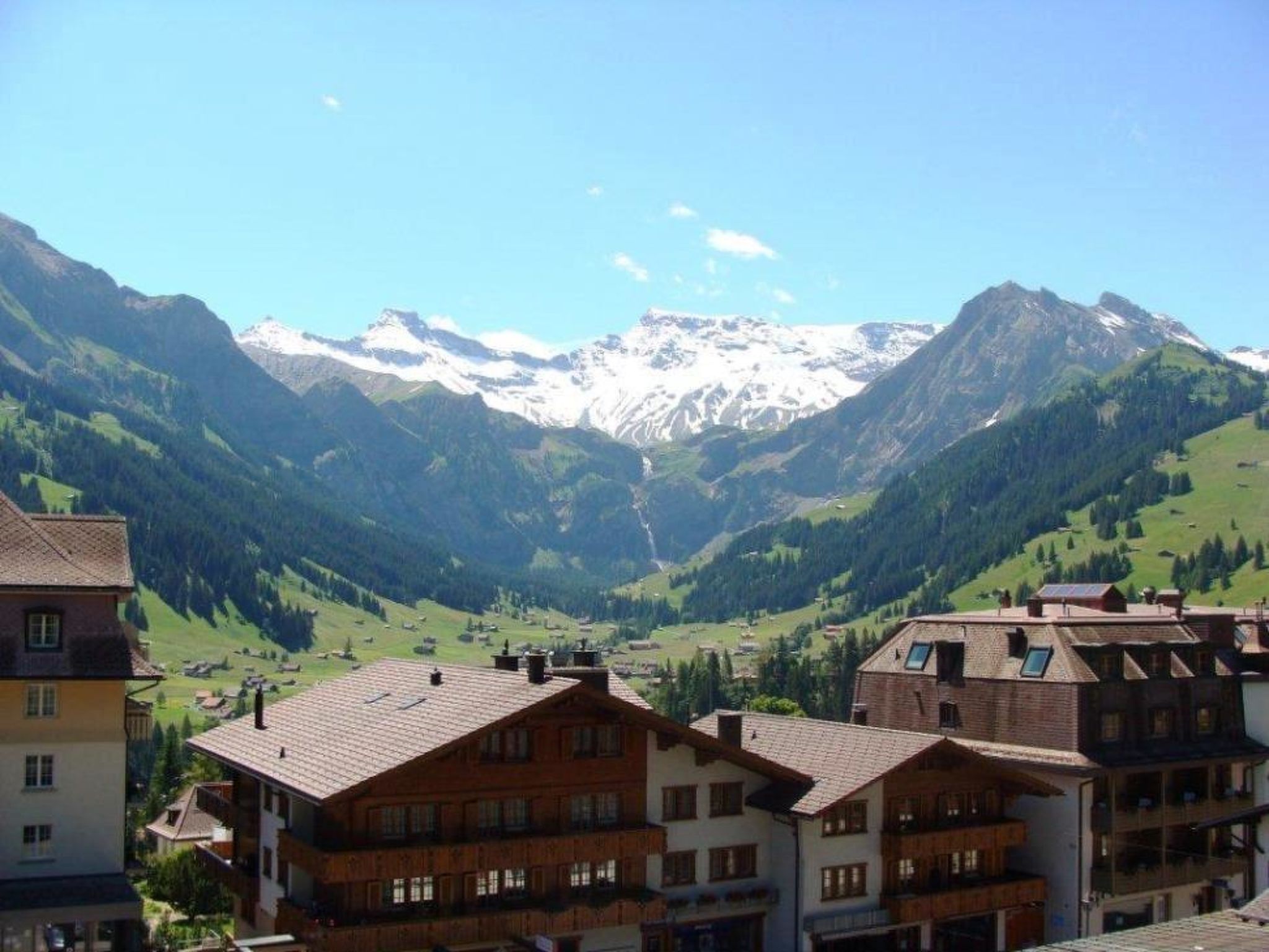 A mountain village with traditional buildings and a view of snow-capped peaks.