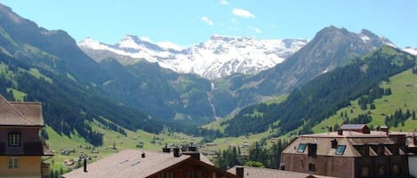 A mountain village with traditional buildings and a view of snow-capped peaks.