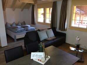 Una habitación moderna amoblada con una cama, un sofá y una mesa de comedor.