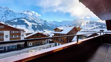A snow-covered mountain landscape with wooden buildings and a balcony overlooking the view.