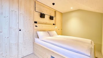 Un dormitorio con cabecera de madera, cama con ropa de cama blanca y armario empotrado.