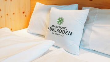 A hotel room with a wooden headboard and white bedding.